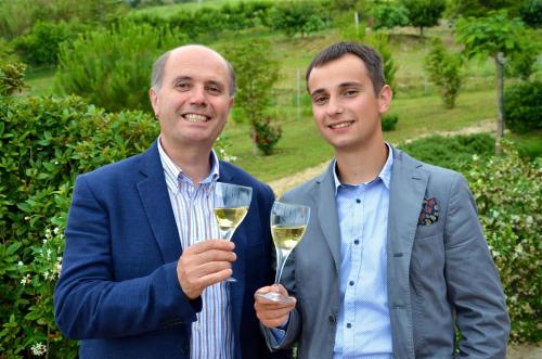 two men are holding a glass of white wine at Country House Villa Geminiani in Montalto delle Marche