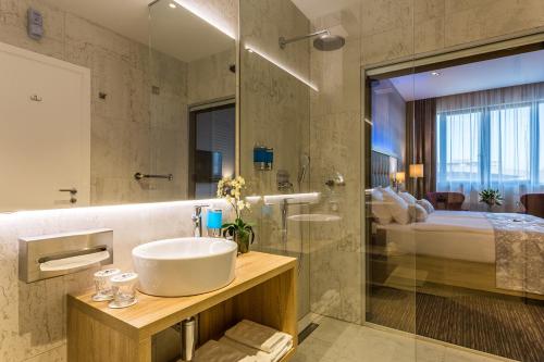 a bathroom with a sink and a shower and a bed at Admiral Hotel in Zagreb