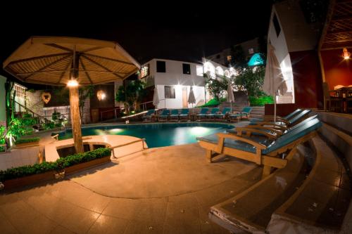 a pool with benches and an umbrella at night at Hotel Villa Jazmin in Ica