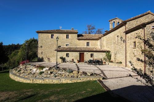 a large stone building with a yard with rocks at Valbuona b&b in Mercatello sul Metauro
