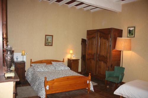 een slaapkamer met een houten bed en een groene stoel bij Presbytère de jonquiere in Lavaur