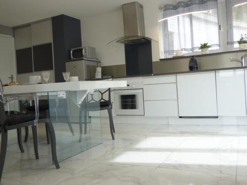 a kitchen with a glass table and some chairs at Suite panoramique à Tulle in Tulle