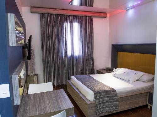 a bedroom with a bed and a table and a window at Rainbow Motel (Adult Only) in Itupeva