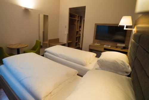 a hotel room with two beds and a flat screen tv at Hotel Marc Aurel - Vienna City Center in Vienna