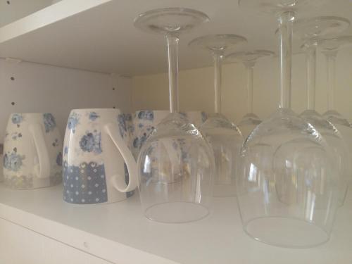a row of wine glasses and vases on a shelf at Apartmán Novákovi in Náchod