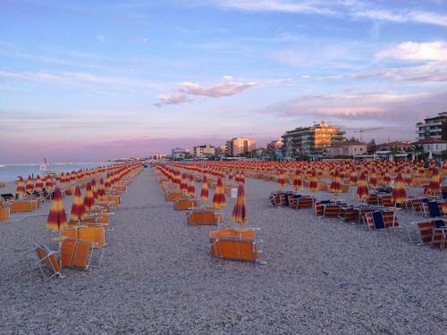 a beach with chairs and umbrellas on the sand at IL NIDO DELLA FORTUNA oasi di pace, relax, storia e mare in Fano