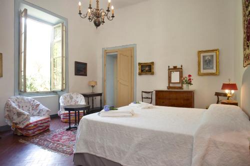 a bedroom with a bed and two chairs and a window at Villa Trenta Prestigious Villa Enchanting Garden in Lucca