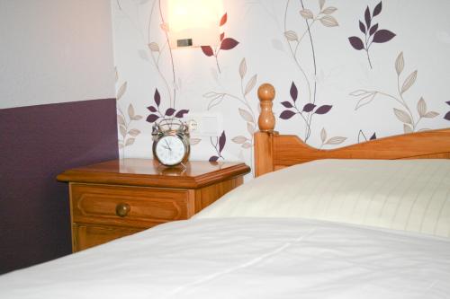 a bedroom with a bed and a clock on a nightstand at Landgasthof Fegetasch in Neukirchen