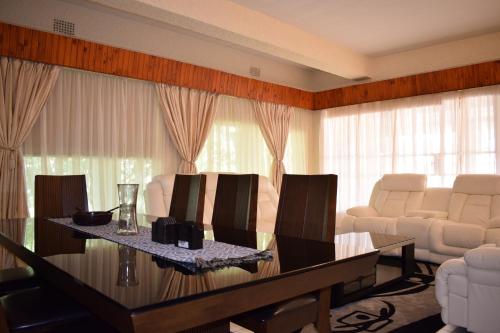 a living room with a table and white chairs at Moye Guest House in Benoni