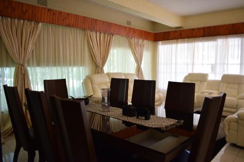 a dining room with a table and chairs and curtains at Moye Guest House in Benoni