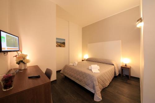 a hotel room with a bed and a desk and a television at B&B Al Picchio in Monopoli