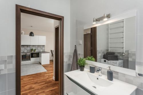 a white bathroom with a sink and a mirror at Chill Apartments City Link in Warsaw