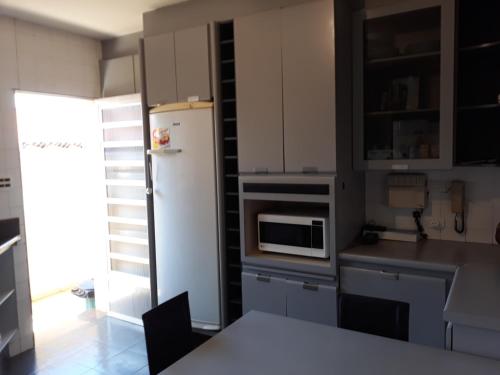 a kitchen with a white refrigerator and a table at Pousada Vale do Rubi in Londrina