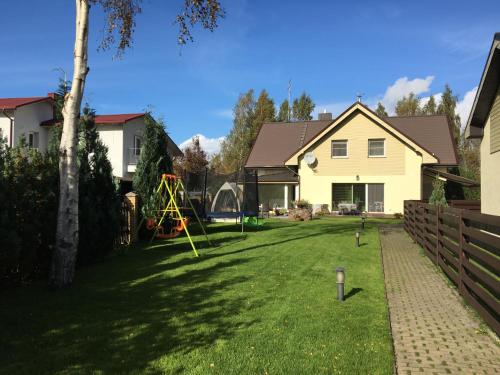 a yard with a house and a playground at Vila Laurus in Palanga
