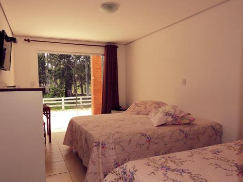 a bedroom with two beds and a window at Hotel Fazenda Menino da Porteira in Ouro Fino