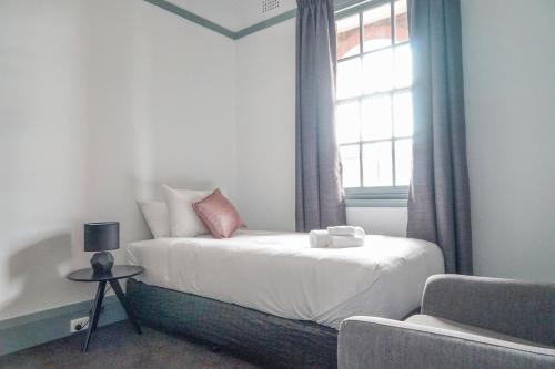 a bedroom with a bed with a window and a couch at Oasis on Beamish Hotel in Sydney