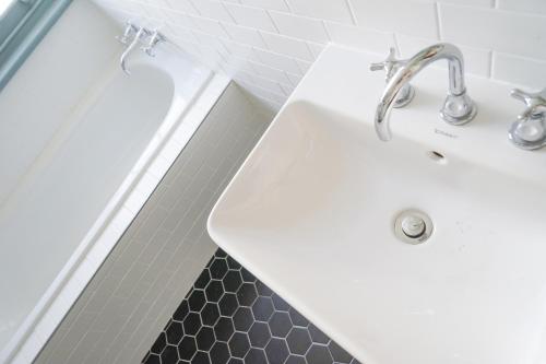 a bathroom with a white sink and a black tile floor at Oasis on Beamish Hotel in Sydney