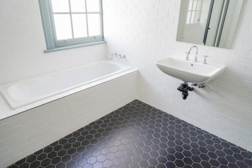 a bathroom with a sink and a white tub and a sink and a mirror at Oasis on Beamish Hotel in Sydney