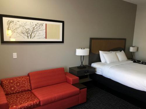 una camera d'albergo con un letto e un divano rosso di Hotel Glenpool a Glenpool
