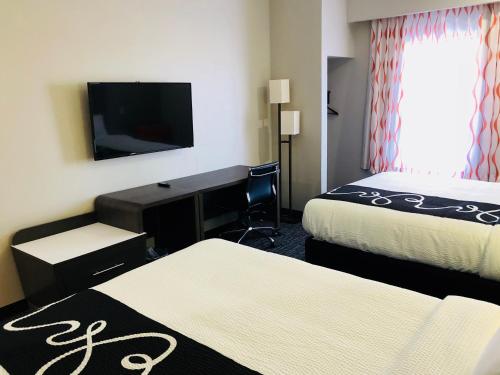 a hotel room with two beds and a desk and a tv at Hotel Glenpool in Glenpool