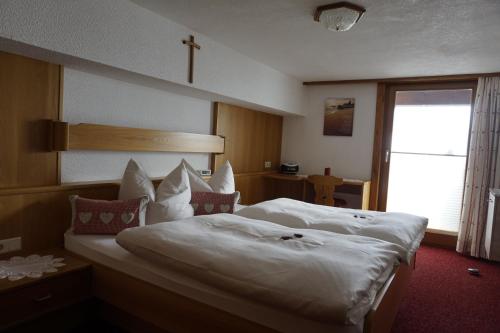 Un dormitorio con una gran cama blanca con una cruz en la pared en Ferienwohnungen Durst Roswitha, en Schattwald