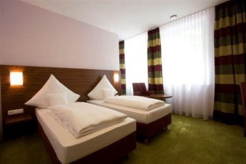 a hotel room with two beds and a window at Gersthofer Auszeit in Gersthofen