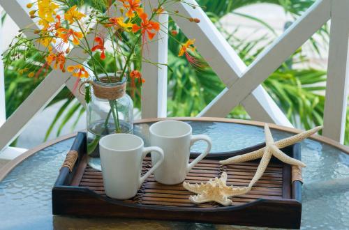 a tray with two mugs and two starfish on a table at Yellow Bird Hotel in Christ Church