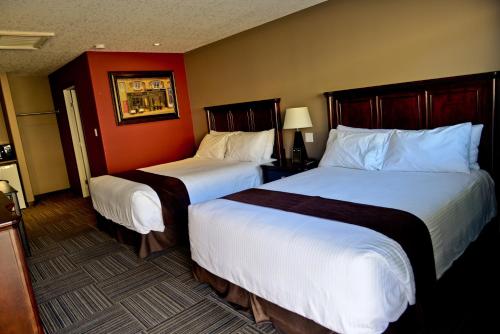 121 Steakhouse & Motel في Assiniboia: سريرين في غرفة الفندق بجدران حمراء