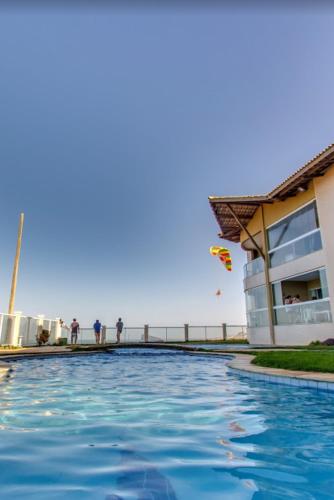 a swimming pool next to a building and the beach at EmanuelleSales - Corretora de Imóveis - "LUXURY RESIDENCES" creci 16949F in Canoa Quebrada