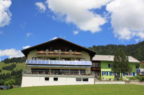 a building with a balcony and a woman standing on it at Katharinahof Ferienpension in Sibratsgfäll
