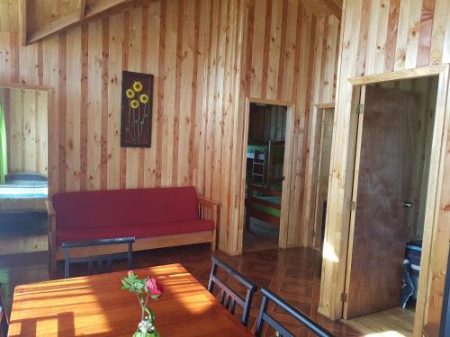 a living room with a red bench and a table at Cabañas Kompatzki in Ancud