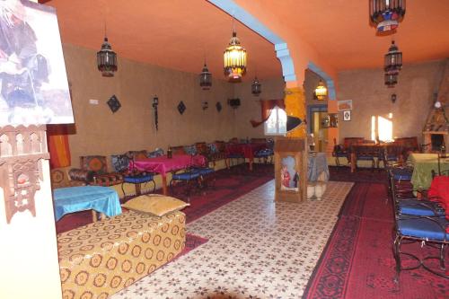 a living room with chairs and tables in a room at Kasbah Du Berger & Piscine in Merzouga