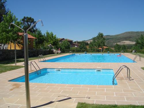 a large swimming pool with blue water in a yard at Quinta de Santo Estêvão Hotel Rural in Aguiar da Beira