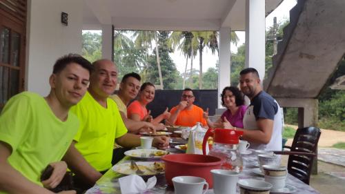 a group of people sitting at a table eating food at Priyanna Guest, Forest view in Polonnaruwa