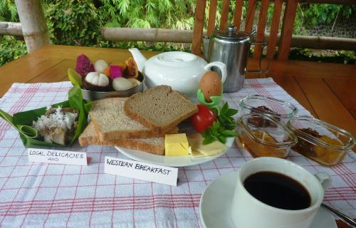 ein Tisch mit einem Teller Essen und einer Tasse Kaffee in der Unterkunft Saraswati Holiday House in Lovina