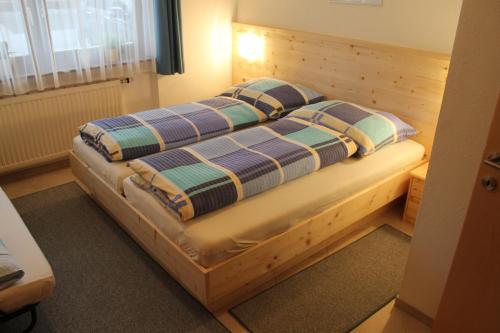 um quarto com uma cama de madeira e 2 almofadas em Appartement Barbara em Sankt Johann in Tirol