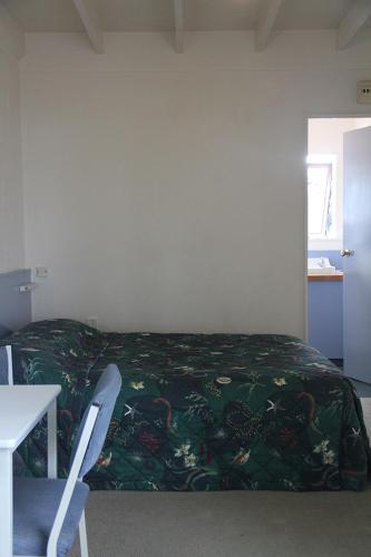 a bedroom with a bed and a table and a chair at Martinborough Motel in Martinborough 