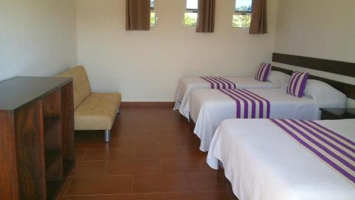 a room with three beds and a chair and windows at Casas Luna y Sol - Casa Sol in Valladolid