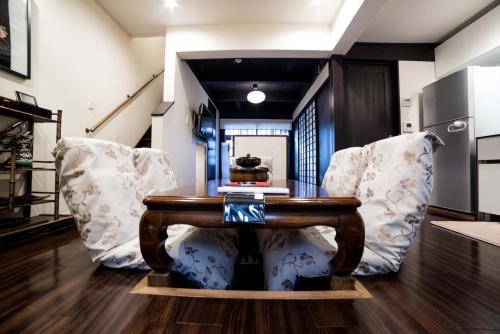 a dining room with a wooden table and two chairs at KYOTO Kazenoya Sara in Kyoto