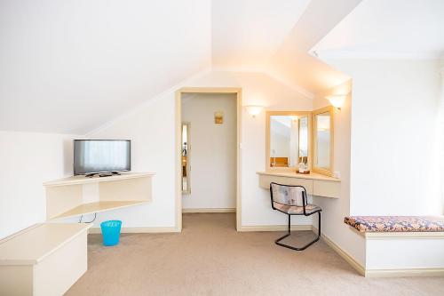 a white room with a tv and a chair in it at Queechy Motel in St Helens