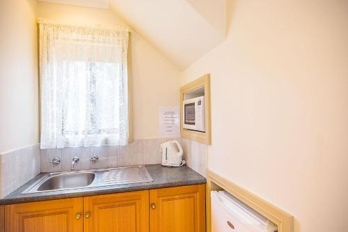 a kitchen with a sink and a microwave at Queechy Motel in St Helens