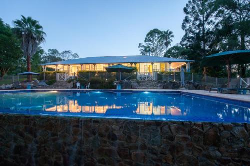 a swimming pool with a house in the background at Samford Lakes Rural Accommodation in Mount Samson