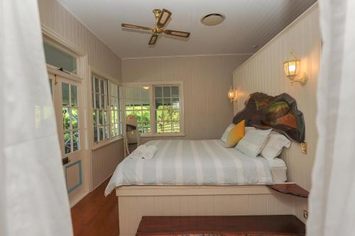 een slaapkamer met een bed, een plafondventilator en ramen bij Samford Lakes Rural Accommodation in Mount Samson