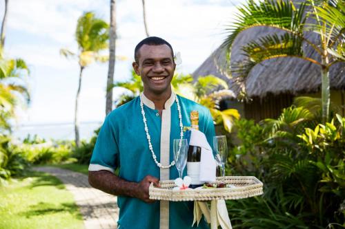 a man holding a plate of food and a bottle of wine at Outrigger Fiji Beach Resort in Korotogo