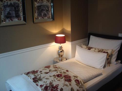 a bedroom with a bed with a lamp on it at Hotel Sir & Lady Astor in Düsseldorf