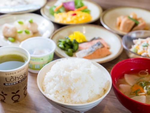 a table topped with plates of food and bowls of rice at Super Hotel Yokkaichi Route 1 in Yokkaichi