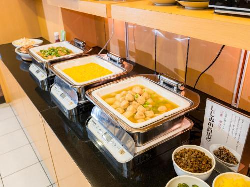 a buffet with several trays of food on a counter at Super Hotel Yokkaichi Route 1 in Yokkaichi