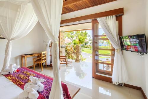 1 dormitorio con 1 cama, TV y ventana en Adi Assri Beach Resorts And Spa Pemuteran, en Pemuteran