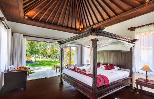a bedroom with a canopy bed in a room at Adi Assri Beach Resorts And Spa Pemuteran in Pemuteran