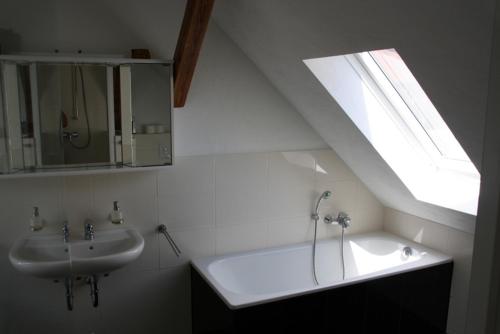 een badkamer met een wastafel, een bad en een raam bij FeWo Bismarck in Wilhelmshaven